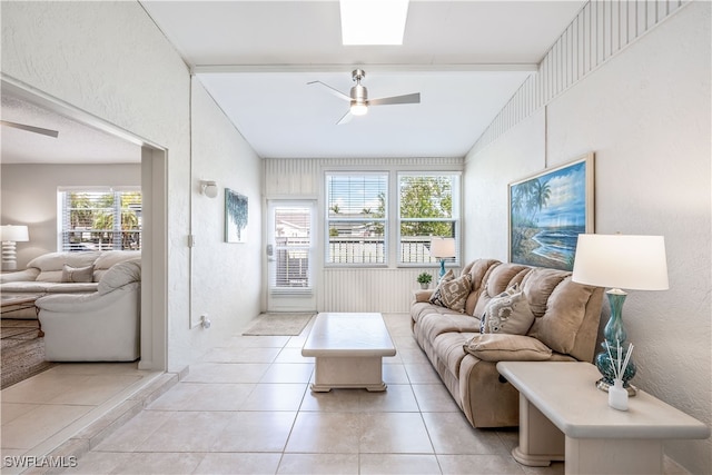 living room featuring a skylight, ceiling fan, and light tile patterned floors