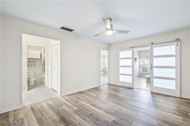 empty room featuring light hardwood / wood-style floors, a barn door, and ceiling fan