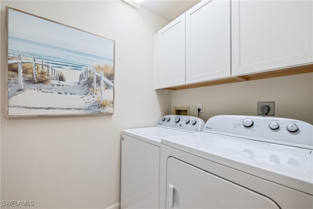 laundry room with cabinets, a textured ceiling, and washer and clothes dryer