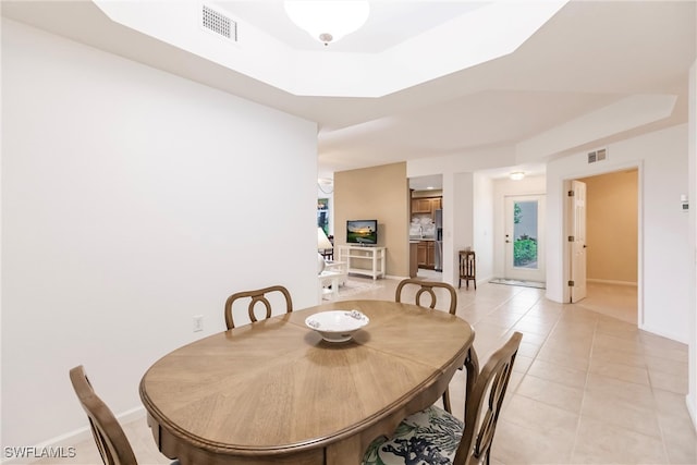 tiled dining space featuring a raised ceiling