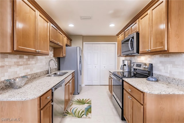 kitchen featuring light stone countertops, stainless steel appliances, backsplash, and sink