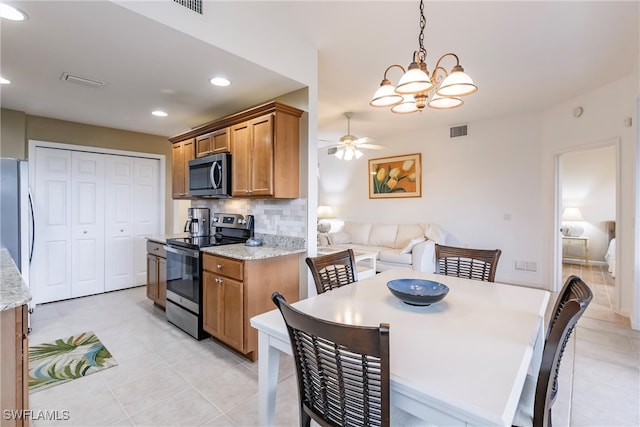 kitchen with decorative light fixtures, light stone counters, stainless steel appliances, and tasteful backsplash