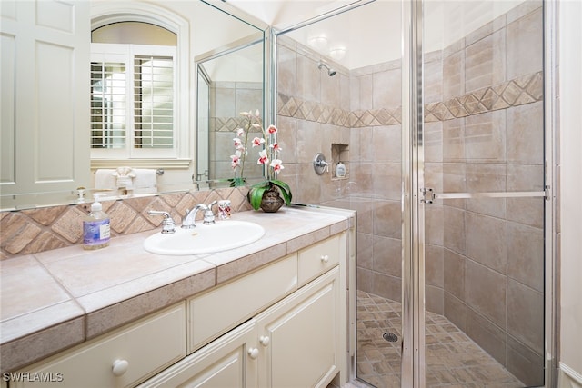 bathroom featuring vanity, tasteful backsplash, and a shower with door