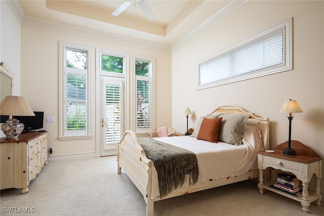 carpeted bedroom with ceiling fan, ornamental molding, and a tray ceiling