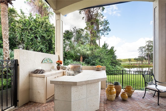 view of patio / terrace featuring area for grilling, sink, a water view, and grilling area