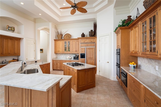 kitchen featuring tasteful backsplash, a kitchen island, stainless steel gas stovetop, paneled built in fridge, and sink