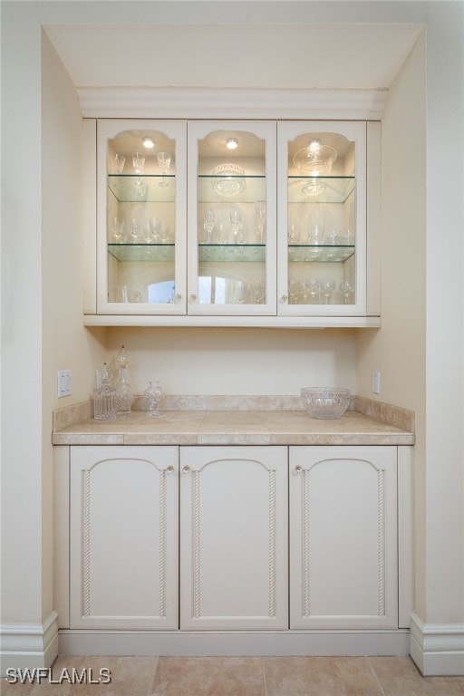 bar with light tile patterned flooring and white cabinets