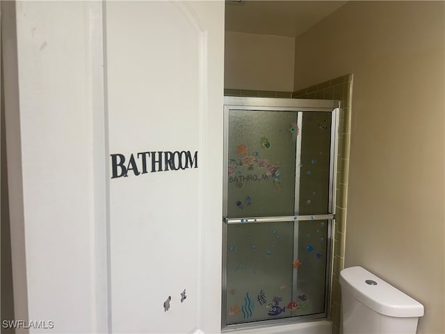 bathroom with a shower with shower door and toilet