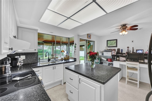 kitchen with decorative backsplash, sink, white cabinets, ceiling fan, and a center island