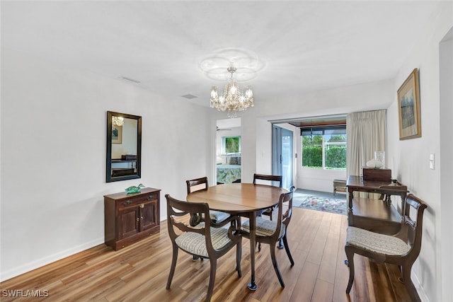 dining space with light wood-type flooring and an inviting chandelier