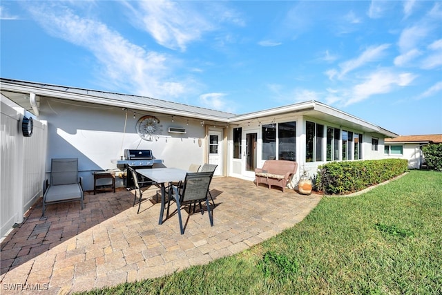 back of property with a sunroom, a yard, and a patio area