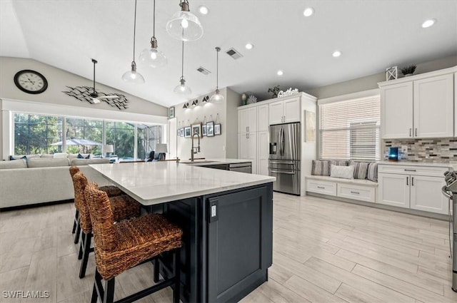 kitchen with pendant lighting, lofted ceiling, white cabinets, a large island, and stainless steel appliances