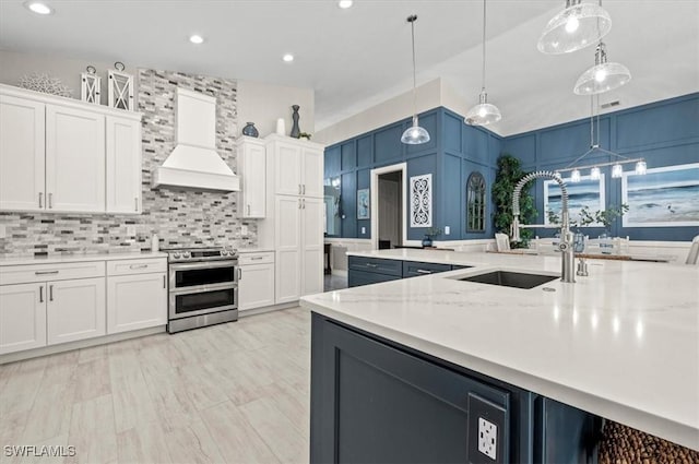 kitchen with white cabinets, decorative light fixtures, premium range hood, and range with two ovens