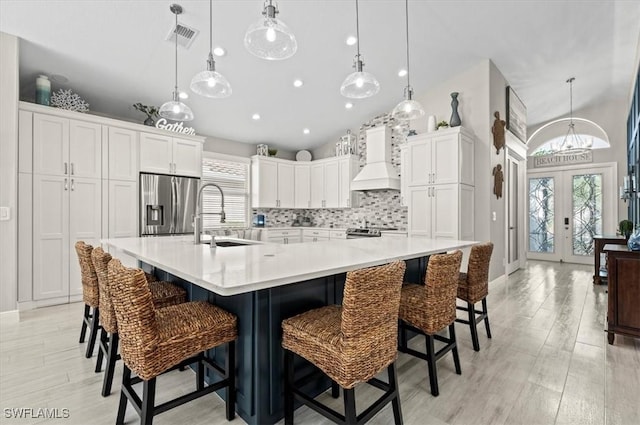 kitchen featuring sink, french doors, a large island with sink, a breakfast bar area, and appliances with stainless steel finishes