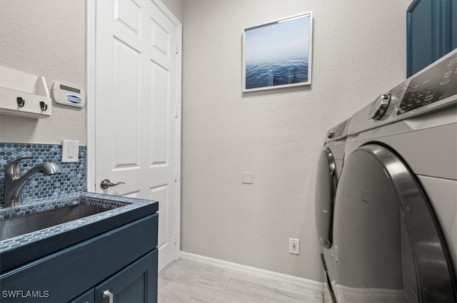 clothes washing area with cabinets, separate washer and dryer, and sink