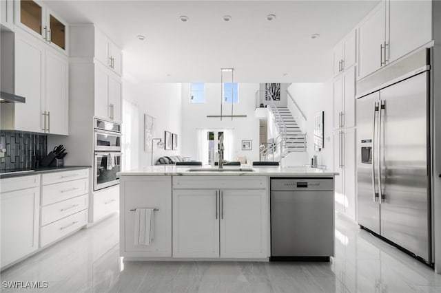 kitchen featuring appliances with stainless steel finishes, white cabinetry, tasteful backsplash, and sink