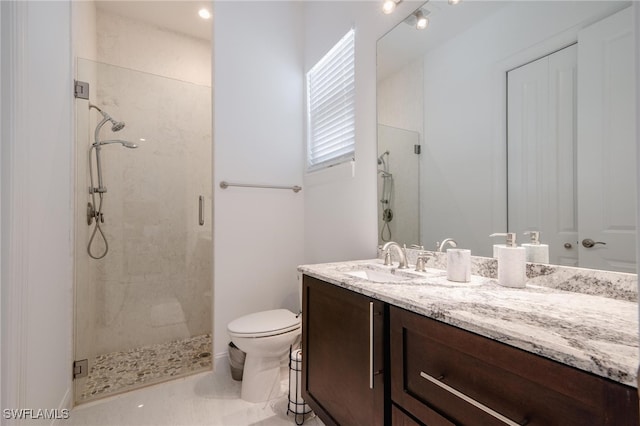 bathroom featuring toilet, a shower with shower door, and vanity