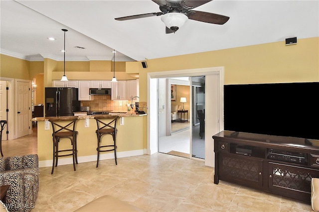 kitchen featuring white cabinetry, black fridge, a breakfast bar, ceiling fan, and hanging light fixtures