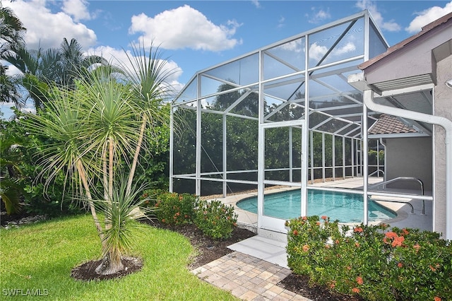 view of pool with glass enclosure and a patio