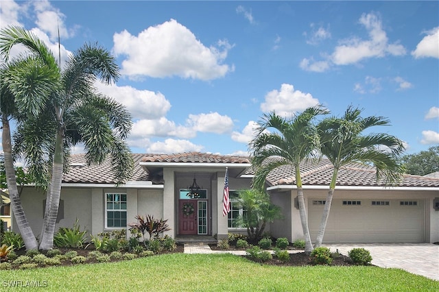 9812 Fathom Ct, Fort Myers, FL 33919 - view of front of property with stucco siding, a tiled roof, a garage, decorative driveway, and a front yard
