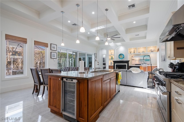 kitchen featuring exhaust hood, high end stainless steel range oven, wine cooler, sink, and ceiling fan