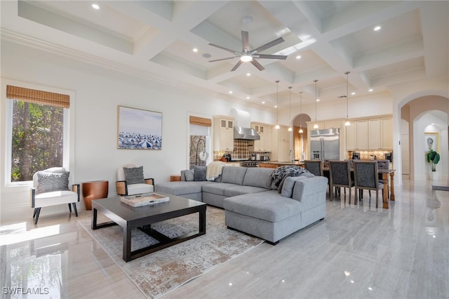 living room with beam ceiling, coffered ceiling, and ceiling fan