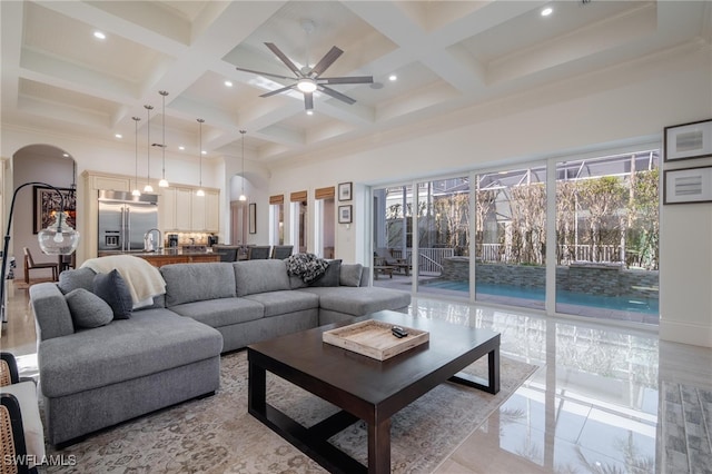 living room with ceiling fan, coffered ceiling, a towering ceiling, and beamed ceiling