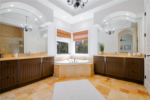 bathroom with vanity, plus walk in shower, ceiling fan with notable chandelier, and a raised ceiling