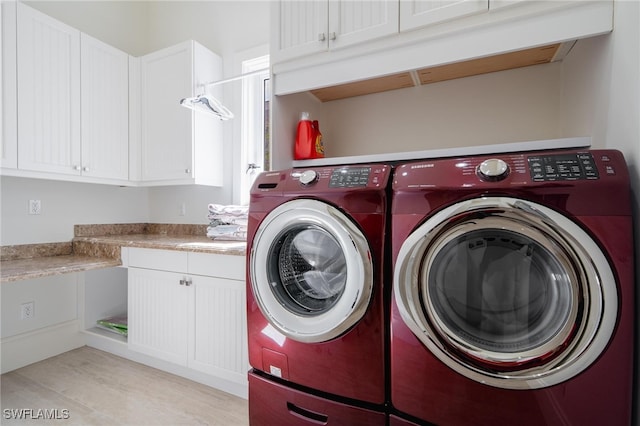 clothes washing area featuring washer and clothes dryer and cabinets