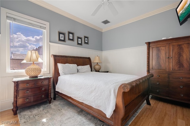 bedroom featuring crown molding, light wood-type flooring, and ceiling fan