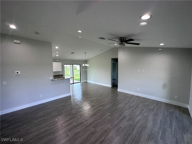 unfurnished living room with vaulted ceiling, dark hardwood / wood-style floors, and ceiling fan with notable chandelier