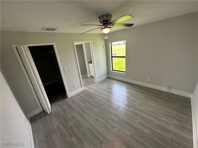 unfurnished bedroom featuring a closet, ceiling fan, light hardwood / wood-style flooring, and a walk in closet