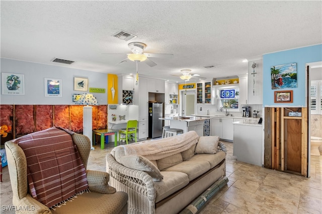 living room featuring a textured ceiling, ceiling fan, and sink