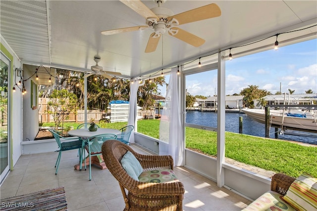 sunroom / solarium with ceiling fan and a water view