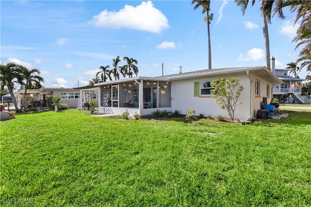 back of property with a sunroom and a yard