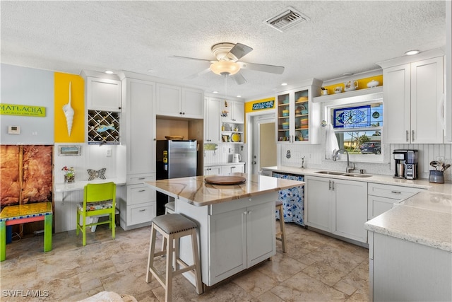 kitchen featuring a kitchen bar, a center island, white cabinetry, and sink