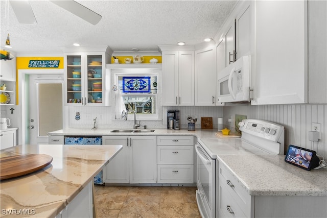 kitchen with white cabinetry, sink, light stone countertops, a textured ceiling, and white appliances