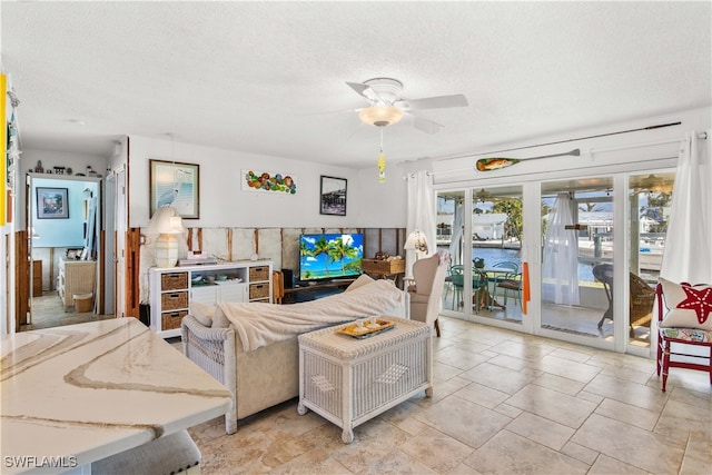 living room featuring ceiling fan and a textured ceiling