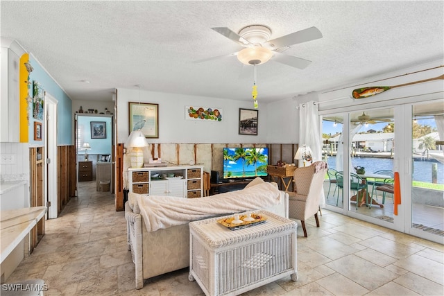 living room with ceiling fan and a textured ceiling