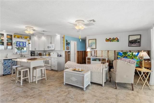 living room with a textured ceiling, ceiling fan, and sink