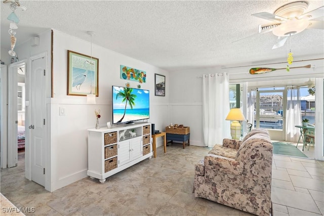 living area featuring visible vents, ceiling fan, and a textured ceiling