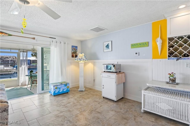 interior space featuring a toaster, a textured ceiling, visible vents, and a ceiling fan