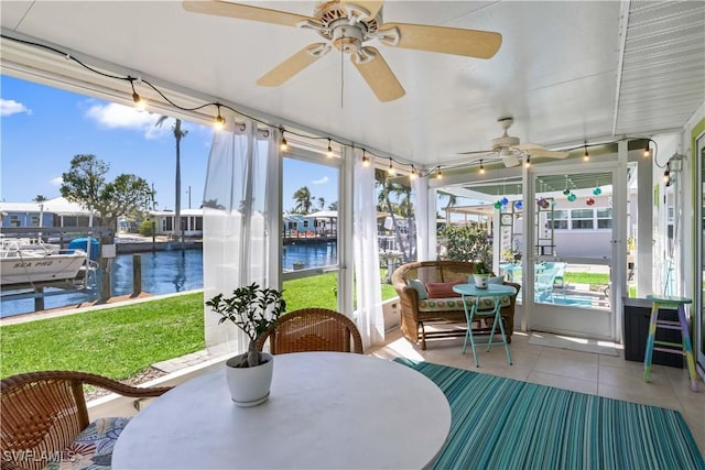 sunroom featuring ceiling fan and a water view