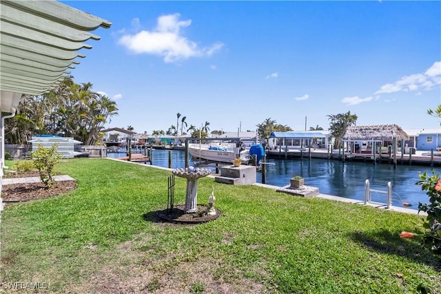 view of dock featuring a water view, boat lift, and a yard