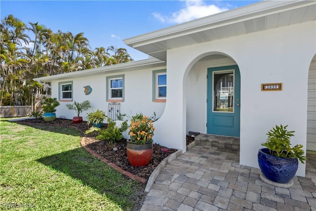 entrance to property featuring a lawn and stucco siding