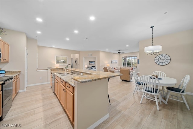 kitchen with appliances with stainless steel finishes, sink, light wood-type flooring, and decorative light fixtures