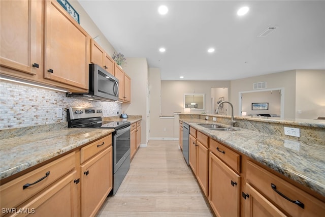 kitchen with light stone countertops, appliances with stainless steel finishes, sink, light hardwood / wood-style flooring, and light brown cabinets