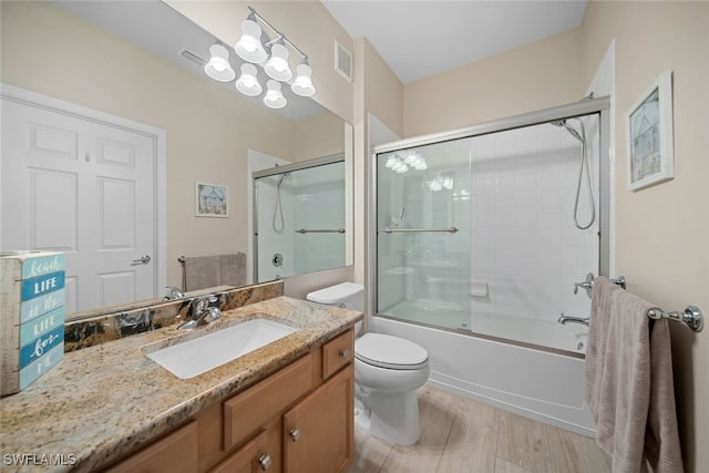 full bathroom with vanity, combined bath / shower with glass door, hardwood / wood-style flooring, and toilet