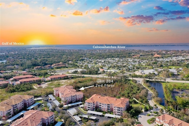 aerial view at dusk featuring a water view