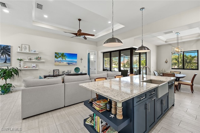 kitchen featuring decorative light fixtures, a raised ceiling, and an island with sink